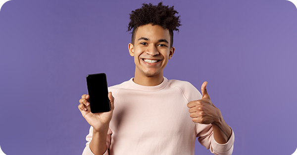 mulher segurando celular com expressão feliz e fazendo símbolo de joia com a mão